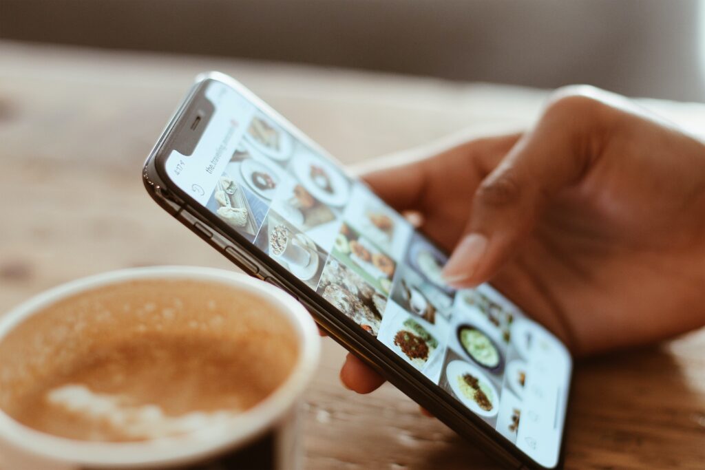 Pessoa rolando o feed do Instagram enquanto toma um café